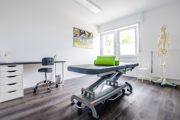 Aufnahme eines Behandlungszimmers einer Physiotherapiepraxis mit Behandlungsliege und Skelett.